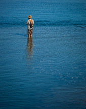 a man standing in the ocean fishing 