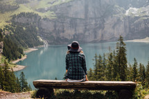 Woman sitting on a bench at a mountain lake