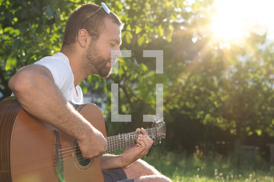 man playing a guitar in a garden 