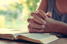a woman praying over an open Bible 