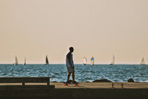 man on a skateboard on a dock and sailboats 