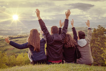 Christian worship and praise. Group of friends hugging outdoors at sunset.