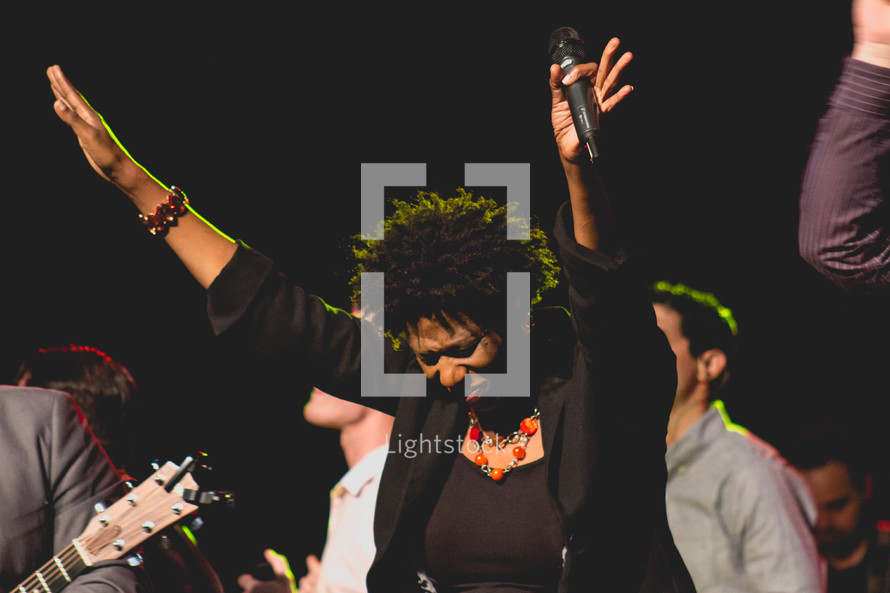 a woman holding a microphone praising God 
