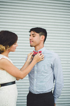 a woman adjusting a man's bow tie 