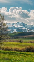 A beautiful mountain range with a cloudy sky in the background. The mountains are covered in snow and the sky is filled with clouds. The scene is peaceful and serene, with a sense of calmness