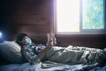 a sick boy lying in bed reading a Bible 