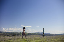 man and woman walking in a field 