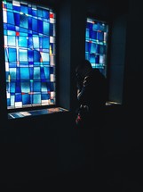 a man praying in front of stained glass windows 