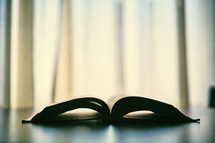 Silhouette of open Bible sitting on table