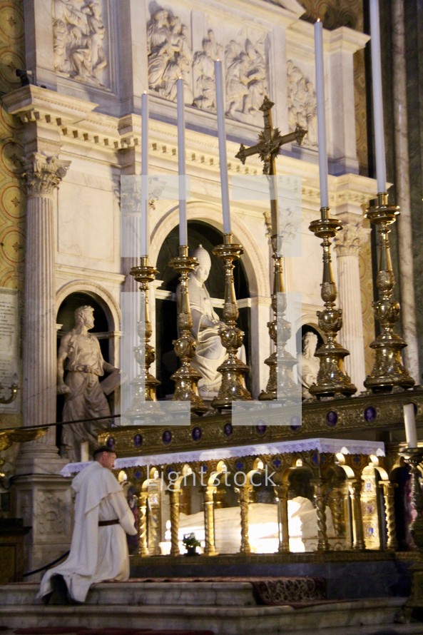 a priest praying in front of a tomb of a saint 