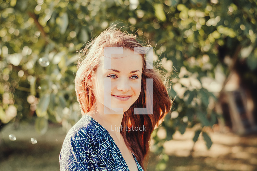face of a smiling young woman in a garden 