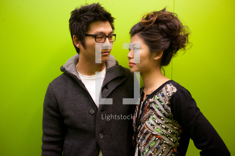 Asian couple against a green wall 