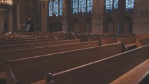 Walking down a row of wood pews inside of a catholic/cathedral church.