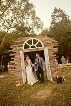 bride and groom walking through doorway arch