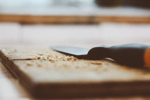 a cutting board and a knife and crumbs 