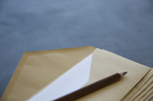 a pencil on a stack of envelopes 
