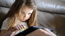 a little girl playing on a tablet 