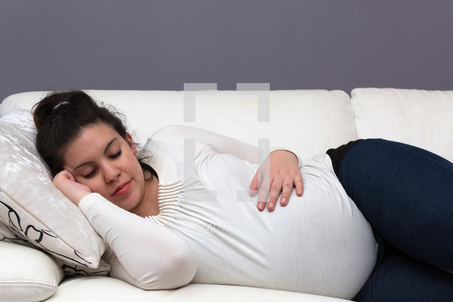 a pregnant woman napping on the couch 