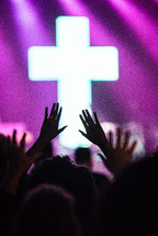 raised hands at a contemporary worship service and cross 