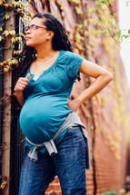 Pregnant African-American Woman leaning against an exterior brick wall