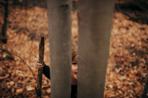 a boy peeking between two trees