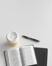 coffee cup, pen, open Bible, and journal on a table 