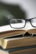 reading glasses on a stack of old books 