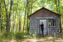 woman entering a cabin in the woods 