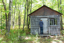 man entering a cabin in the woods 