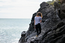 young woman walking on rocky shoreline 
