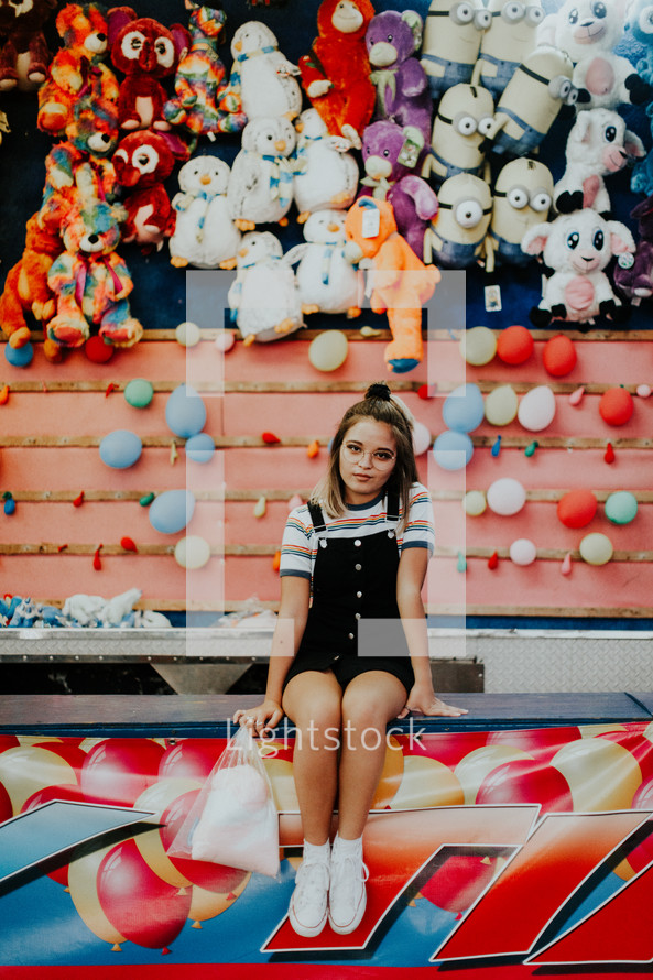 a teen girl at a carnival game booth at a fair 