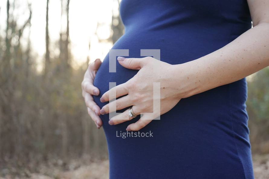 a woman with her hands on her pregnant belly 