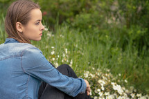 a young woman sitting quietly outdoors 