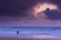 woman standing on a beach under a cloudy sky