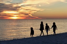 silhouettes of children playing on a beach at sunset 
