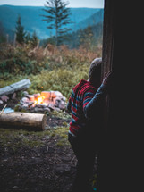 boy standing in a doorway near a campfire 