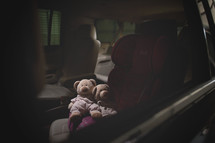 teddy bears in a booster seat in a car 
