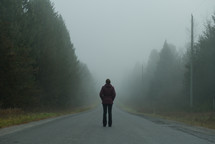 a woman standing on a foggy road 