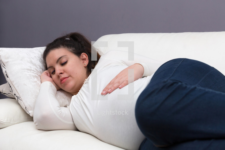 a pregnant woman napping on the couch 