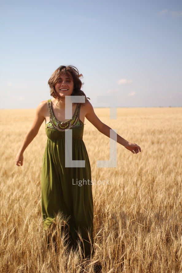 a young woman standing in a field of golden wheat 