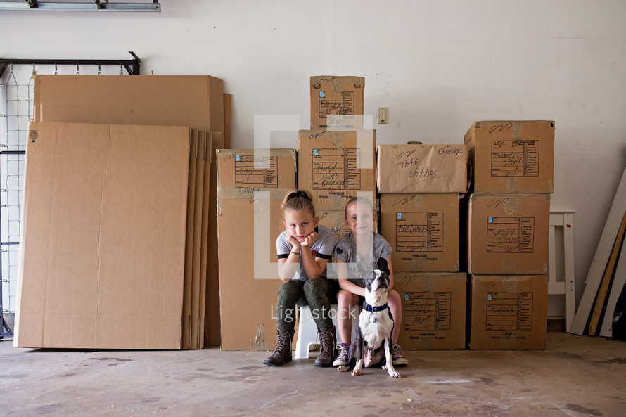 children and a dog next to moving boxes 