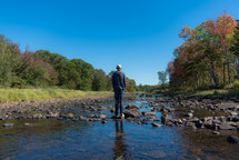 young man standing on rocks in a river 