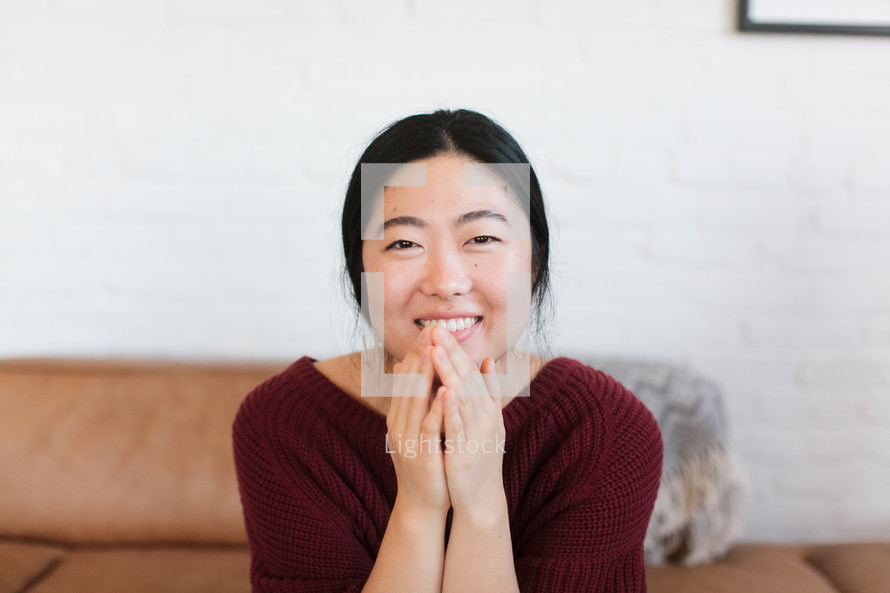 portrait of a smiling woman with her hands to her face 