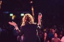 woman on stage holding a microphone 
