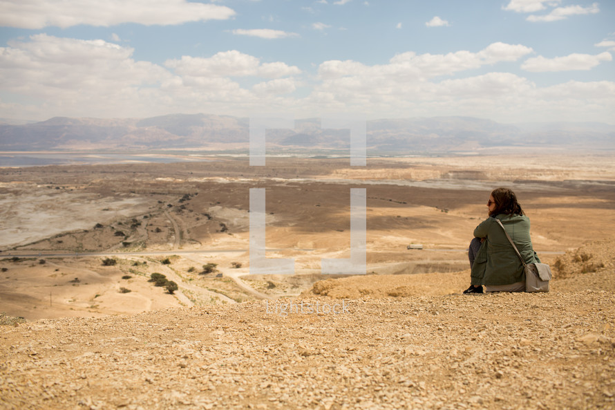 a woman at the edge of a cliff looking out over a canyon in Israel 