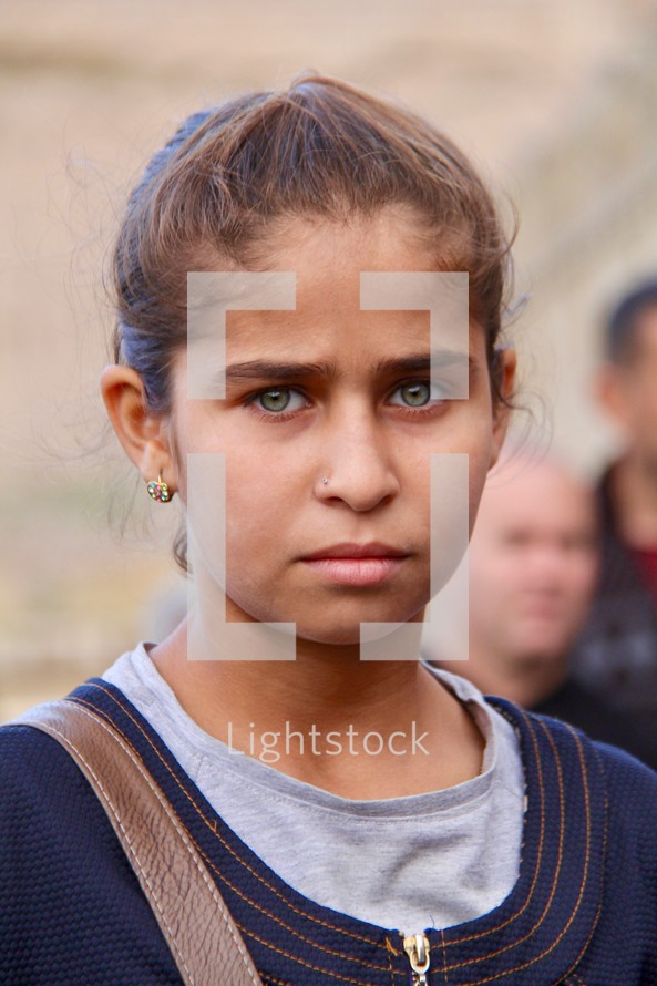 Face of a stoic green eyed teenage Yazidi girl 