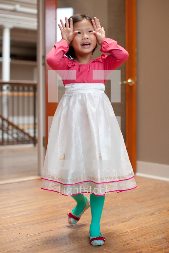 Asian girl child in a dress making faces 