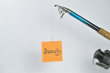 A fishing pole with a piece of paper with the word beauty on it 