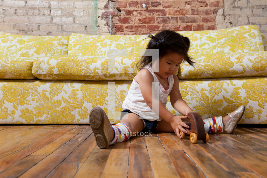 Asian toddler girl on the floor with a toy car 