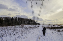 a person walking up a hill in snow under power lines 